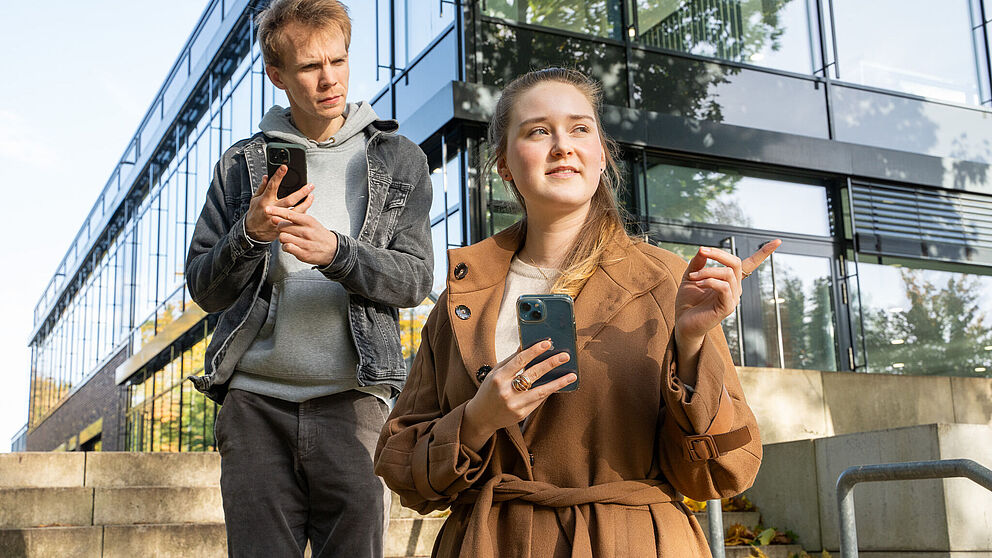 Zwei Menschen mit Handys zeigen sich den Weg