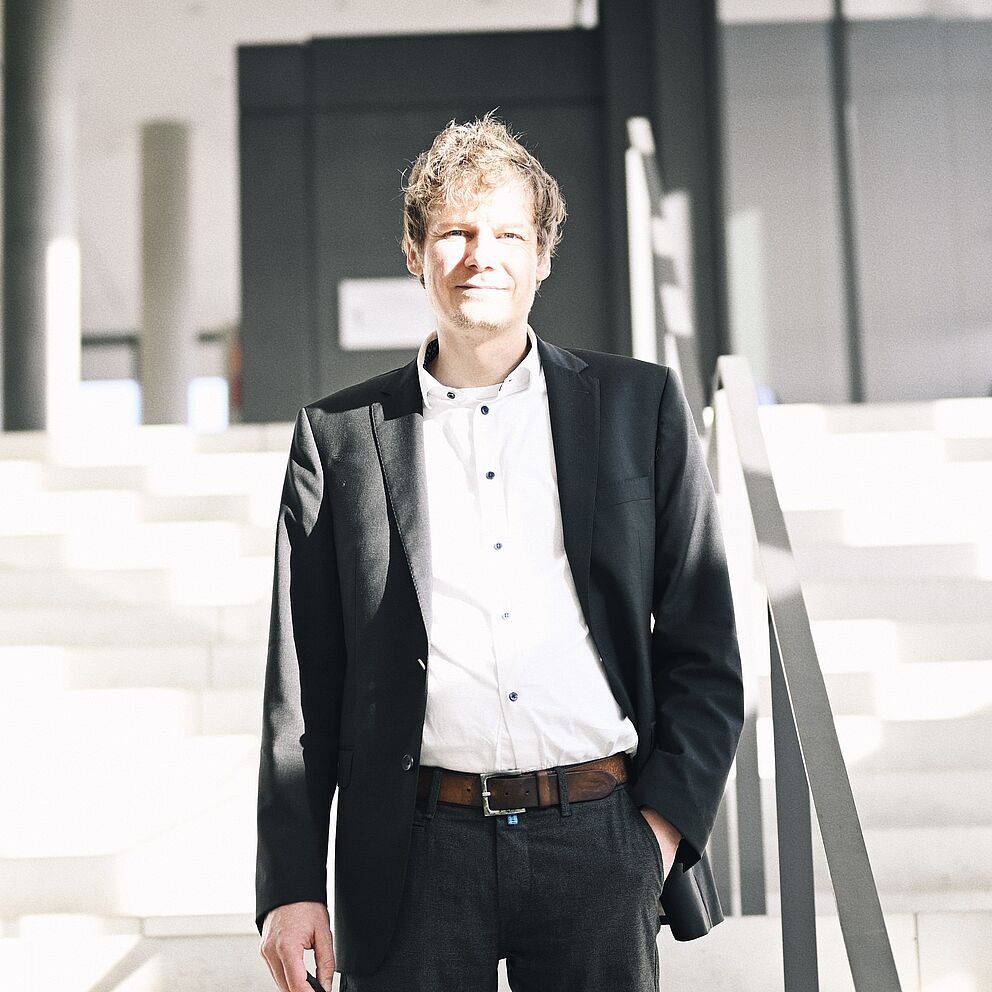 Personalbild des Digitalhistorikers Dr. Martin Schmitt auf Treppe stehend an der Universität Paderborn