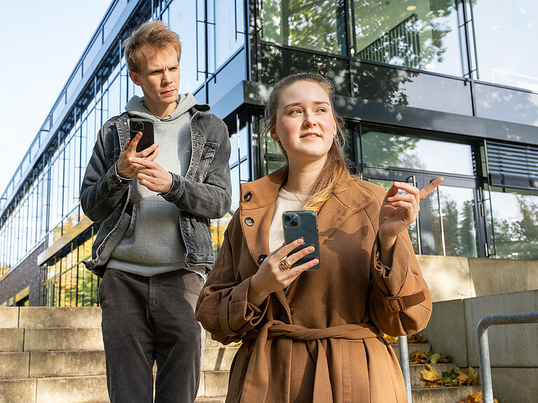 Zwei Menschen mit Handys zeigen sich den Weg