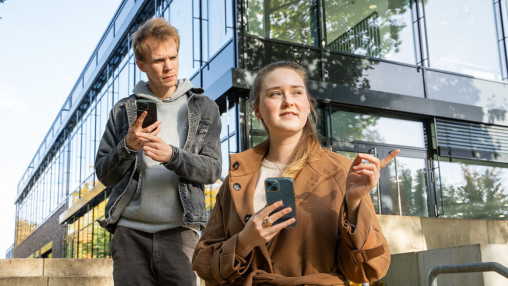 Zwei Menschen mit Handys zeigen sich den Weg