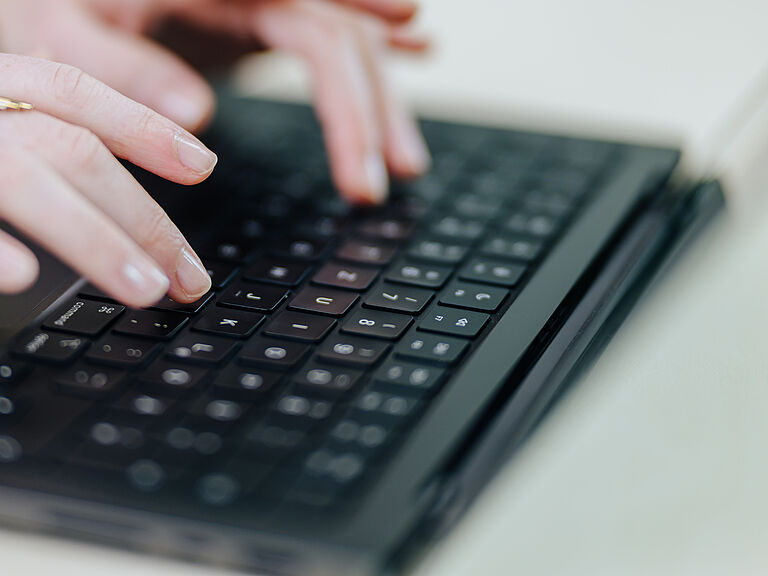 Zwei Hände auf einer Tastatur an einem Laptop.