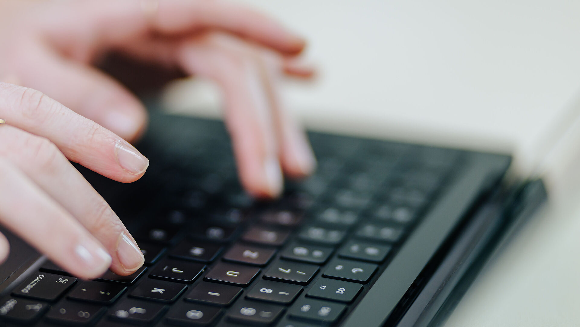 Zwei Hände auf einer Tastatur an einem Laptop.