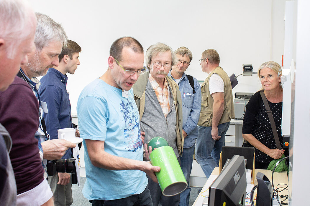 Foto (Markus Allgaier): Physikerinnen und Physiker beim Besichtigen und Begreifen der Experimente.