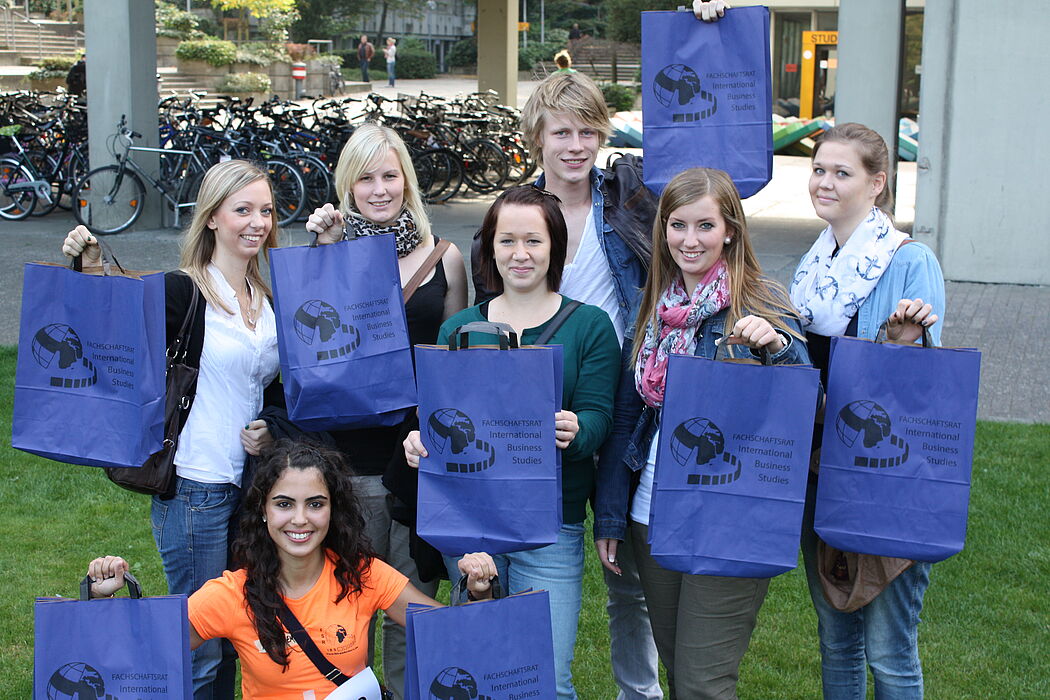 Foto (Universität Paderborn, Patrick Kleibold): Die IBS-Studentin Melten Akpinar (l. unten) überreichte den Erstsemestern Patricia Lempa (v.l.), Verena Arens, Sabrina Finkeldei, Lukas Tenge, Jennifer Müller und Katharina Bergener ein Studienstartset u.