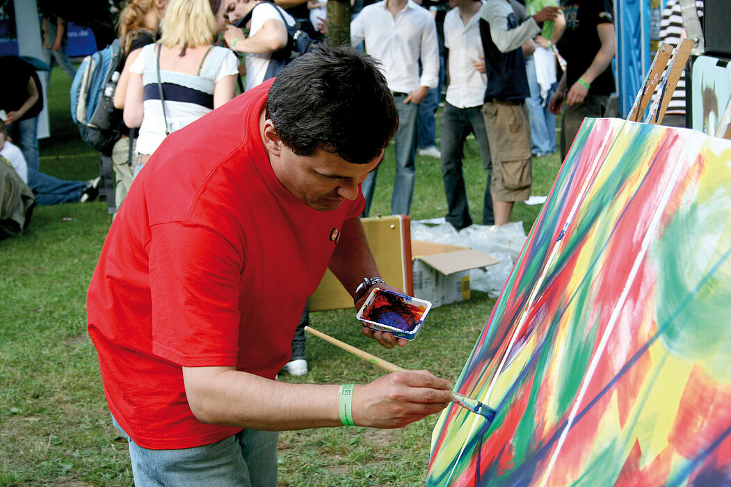 Foto (Universität Paderborn): Der Paderborner Künstler Bernward Schäfers malt das „Farbfestival“.