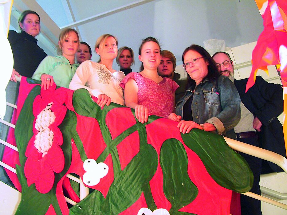 Foto: Treppe mit roter Fahne, von links: Anke Wester, Sarah Flüchter, Sonja Schröder, Eva Lammert, Maren Voigt, Christine Braun, Benedikt Breuer, Prof. Dorothea Reese-Heim, Museumsleiter Wulff E. Brebeck