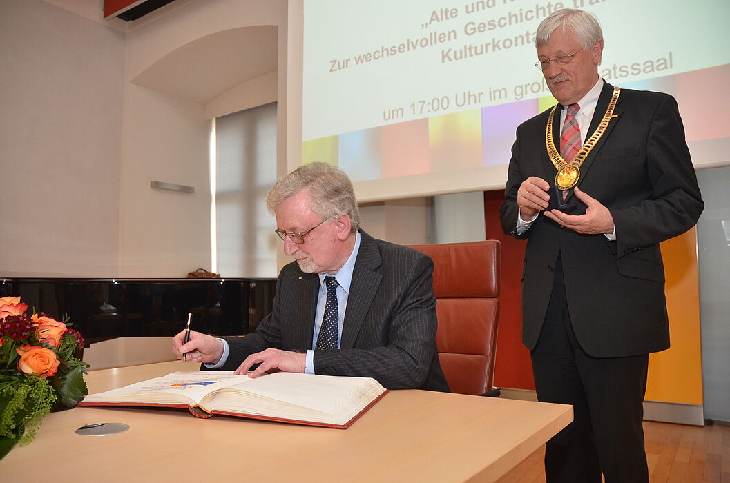 Foto (Stadt Paderborn): Prof. Dr. phil. Dr. h. c. mult. Peter Freese, Universität Paderborn, trägt sich in das Goldene Buch der Stadt Paderborn ein; rechts Bürgermeister Heinz Paus.