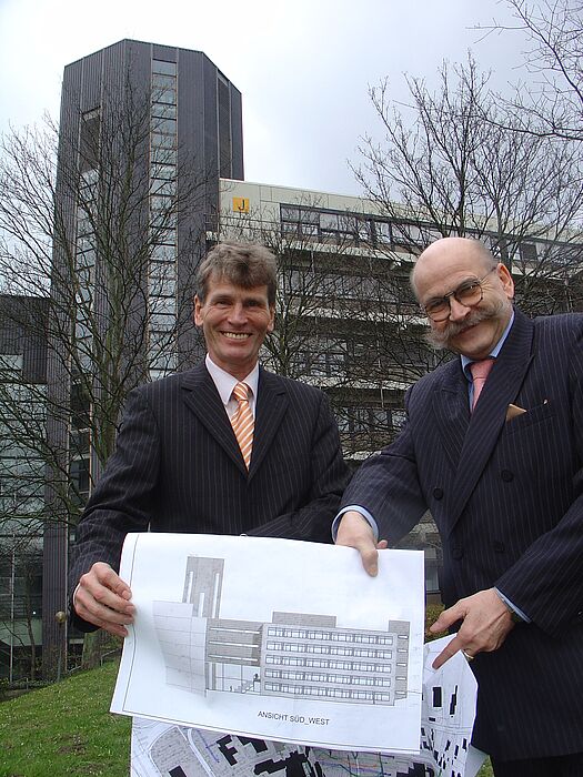 Foto (Tibor Werner Szolnoki, Universität Paderborn): Präsident Prof. Dr. Nikolaus Risch (li.) und Kanzler Jürgen Plato bei der künftigen Baustelle mit der Ansicht des geplanten Laborgebäudes auf dem Uni-Campus.