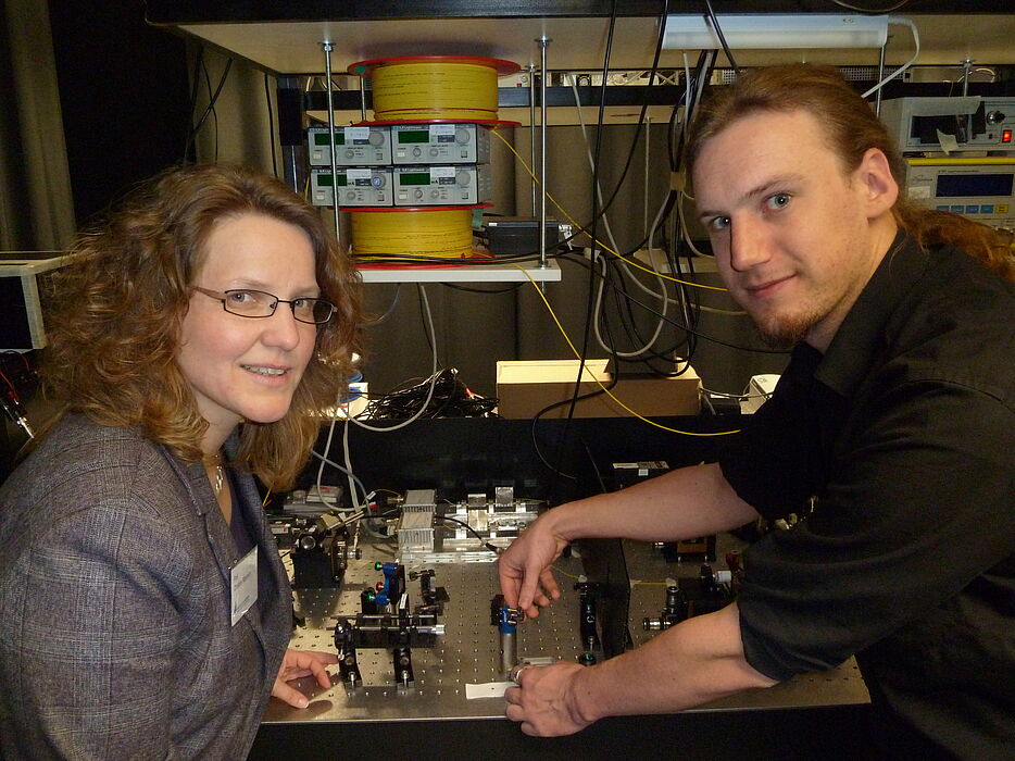 Foto (Universität Paderborn): Christine Silberhorn und Andreas Schreiber präsentieren stolz ihr neues Experiment zur Realisierung von Quantenspaziergängen.