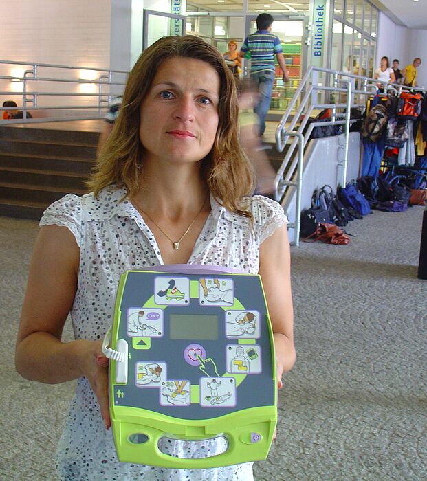 Foto (Tibor Werner Szolnoki): Diana Riedel hält einen Defibrillator in den Händen. Dieser ist mit einer Sprechfunktion sowie erklärenden Bildern ausgestattet und somit auch durch Laien nutzbar. Insgesamt sechs von diesen lebensrettenden Geräten gibt e