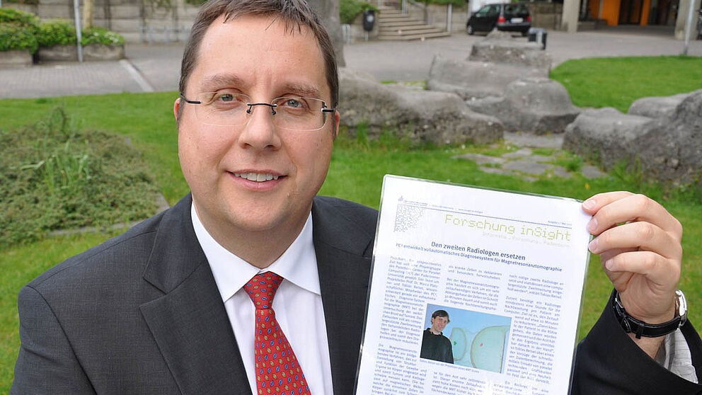 Foto (Nadija Pejic, Institut für Informatik): Prof. Dr. Marco Platzner mit der ersten Ausgabe von „Forschung inSight“.