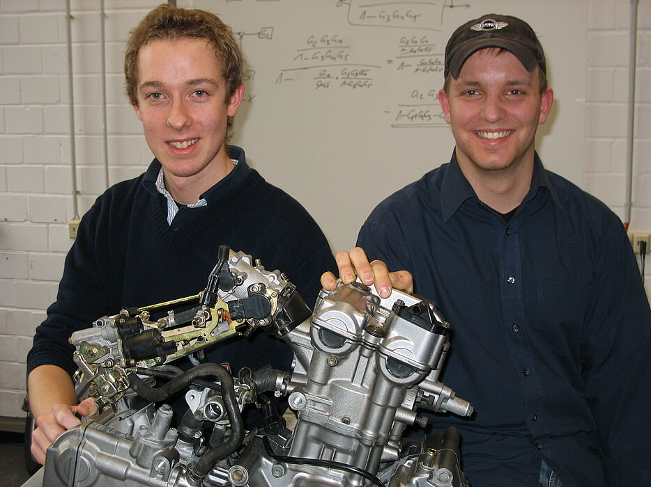 Foto (Christiane Bernert): Lars Heisel (li.) und Nils Gerhart mit dem Motor des Boliden, der in einer Werkstatt auf dem Uni-Campus entsteht. Der Suzuki SV 650-Motor wird später mit Bio-Ethanol angetrieben, das Auto bekommt einen Turbolader und Allrad-Ant