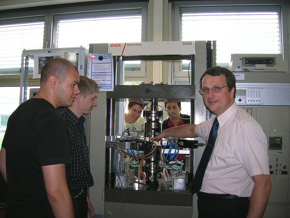 Foto (Julius Kolossa): Prof.-Dr. Ing. Hans Jürgen Maier (rechts) diskutiert mit (v. l.) Dr. Demircan Canadinc, Dipl.-Ing. Sergej Tschumak, Dipl.-Ing. Stefan Wilmanns und Dipl.-Ing. Ismail Caylak das Prinzip der Werkstoffprüfung bei hohen Temperaturen.