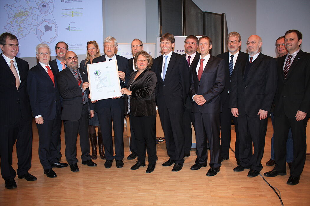 Foto (Referat Presse und Kommunikation, Universität Paderborn, Frauke Döll): NRW-Innovationsministerin Svenja Schulze übergibt Bürgermeister Heinz Paus und den anderen Akteuren und Partnern von FIT.Paderborn das zdi-Gütesiegel.