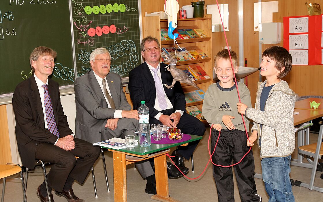 Foto (Patrick Kleibold, Universität Paderborn): Zwei Schüler aus der ersten Klasse der Domschule erklären Prof. Dr. Nikolaus Risch, Heinz Paus und Dr. Kurt Beiersdörfer die Technik des Seilzugs.
