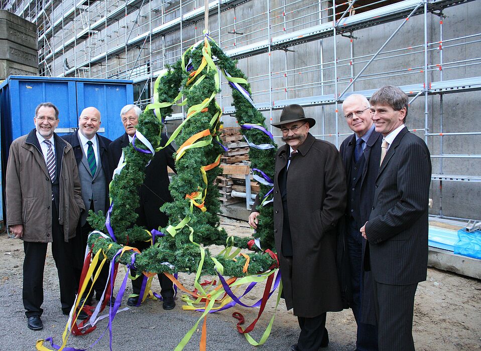 Foto (Universität Paderborn, Martin Decking): Nach dem Richtfest wurde der bunt geschmückte Richtkranz hoch in die Luft gezogen. Über den bereits deutlich erkennbaren Baufortschritt freuen sich Heinz Krommen (Ministerium für Innovation, Wissenschaft u