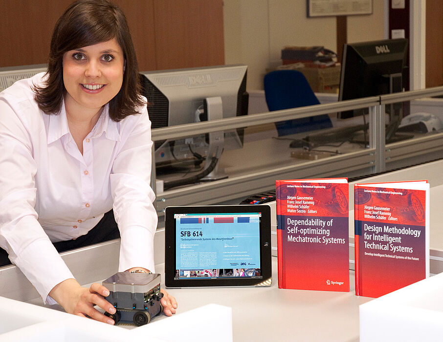 Foto (Universität Paderborn, Heinz Nixdorf Institut): Mareen Vaßholz, Geschäftsführerin des SFB 614, mit einem Miniaturroboter, der als Demonstrator für die Ergebnisse der Forschungsarbeiten sowie der Abschlusspublikationen dient.