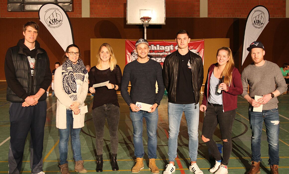 Foto (Universität Paderborn, Björn Heerdegen): Hatten Losglück: Till Gloger (links) und Luca Kahl (3. v. r.) von den Uni Baskets Paderborn überreichen Gutscheine für den Hochschulsport und Freikarten zu einem Heimspiel ihres Teams an die Gewinner.