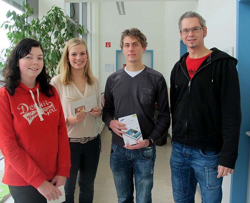 Foto (Universität Paderborn, Cinderella Schröder): Jörn Sickelmann (rechts) bei der Übergabe der Sachpreise. Die glücklichen Gewinner/innen (v. re.): Jens Beutel, Alina Jonas und Janine Hamm.
