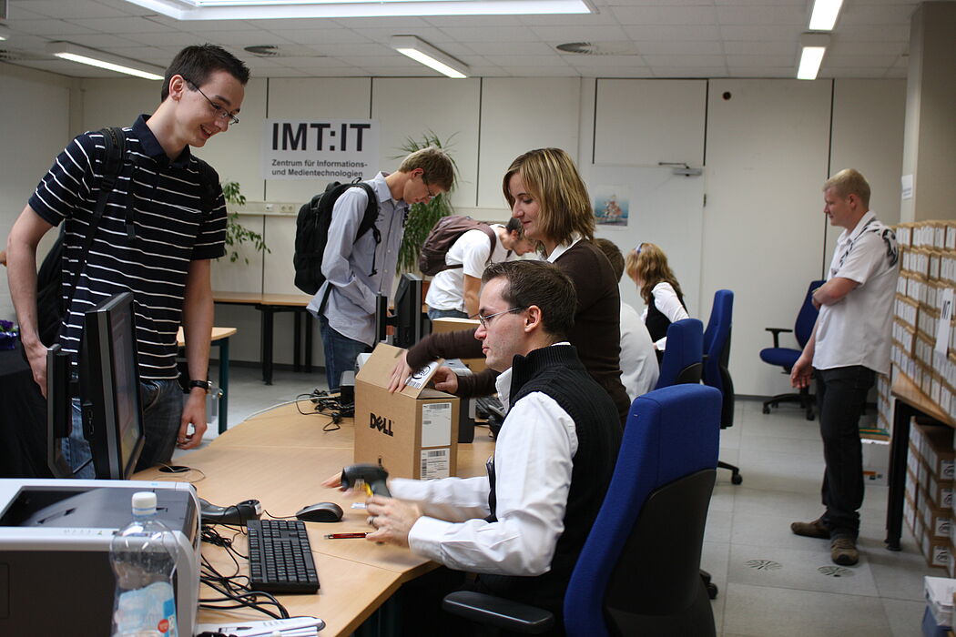 Foto (Frauke Döll): Auszubildende Jeannette Schopny und Sebastian Porombka, studentische Hilfskraft des IMT, statten die Erstsemester mit Netbooks und Informationen aus.