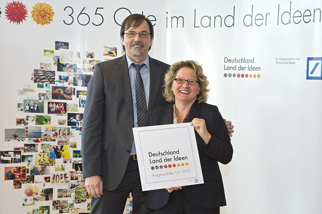 Abbildung (Quelle: „Deutschland – Land der Ideen/Uwe Völkner, Fotoagentur FOX“): Svenja Schulze, Ministerin für Innovation, Wissenschaft und Forschung des Landes Nordrhein-Westfalen, überreicht Prof. Dr. Gregor Engels, Vorstandsvorsitzender s-lab