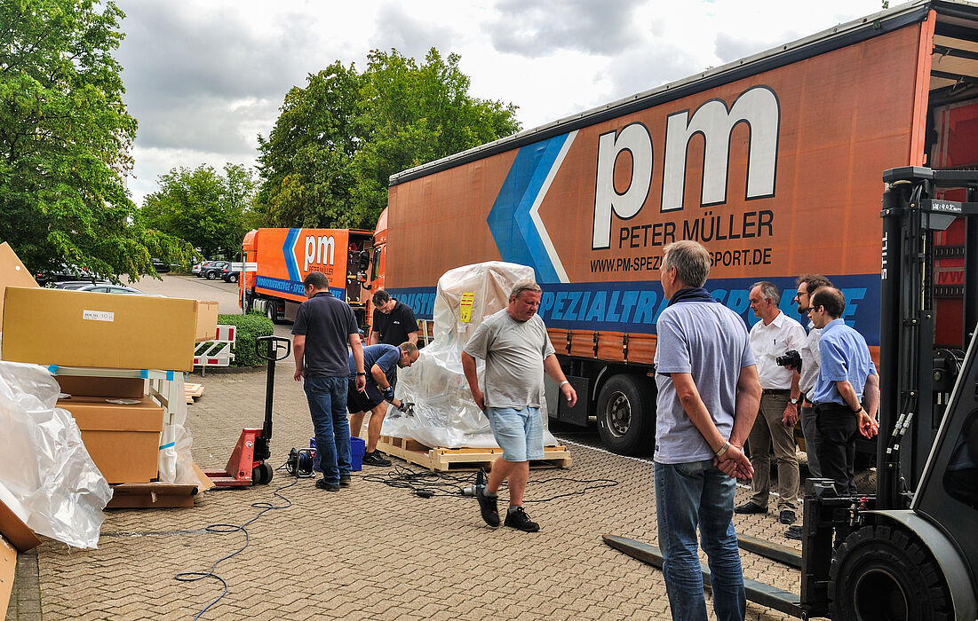 Foto (Department Physik): Das neue Transmissionselektronenmikroskop des Departments Physik wird angeliefert. Die Physiker beobachten gespannt, wie die Erste von neun Kisten ausgepackt wird.