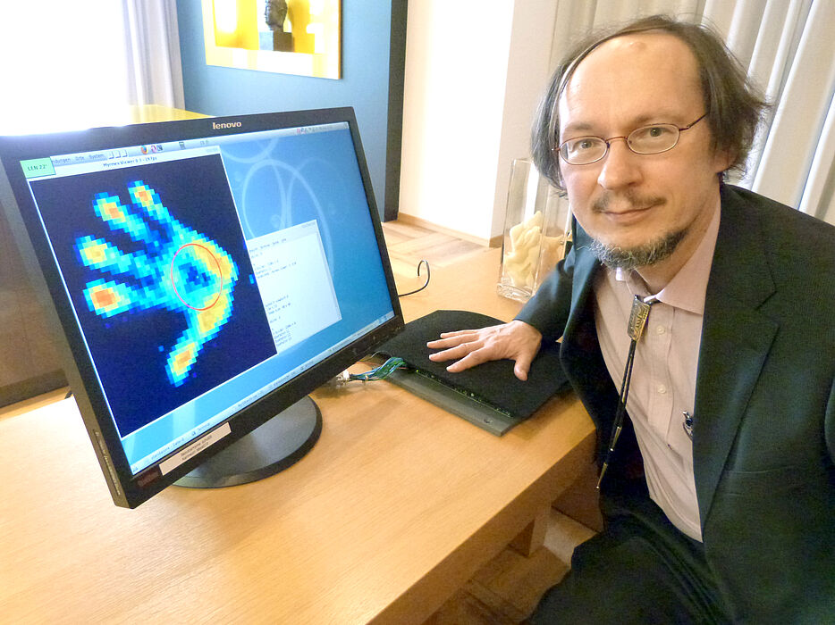 Abbildung: Forscherinnen und Forscher befassen sich in dem Projekt auch mit Sensortechnik. Prof. Dr. Helge Ritter demonstriert "Myrmex". Der Forschungsprototyp erkennt den unterschiedlichen Druck, den Objekte ausüben, die darauf platziert werden. Foto: U