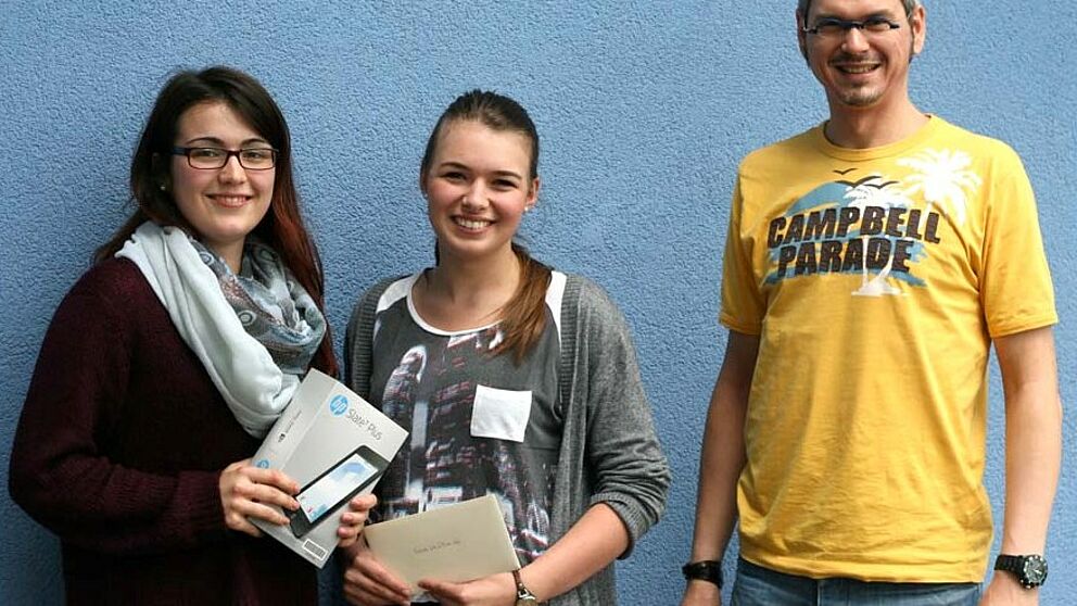 Foto (Universität Paderborn, Cinderella Schröder): Zwei der sieben glücklichen Gewinner/innen: Michele Baldes und Franziska Schmidt sowie Jörn Sickelmann (stellv. Leiter der ZSB) bei der Übergabe der Sachpreise.