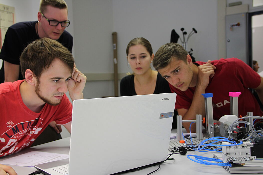 Foto (Fachgebiet Technikdidaktik): Konzentrierte Gesichter bei der Bearbeitung der Aufgabe, die Lehramtsstudent Fabian Weber (stehend) gemeinsam mit einem Kommilitonen für die Radmontage entwickelt hatte.