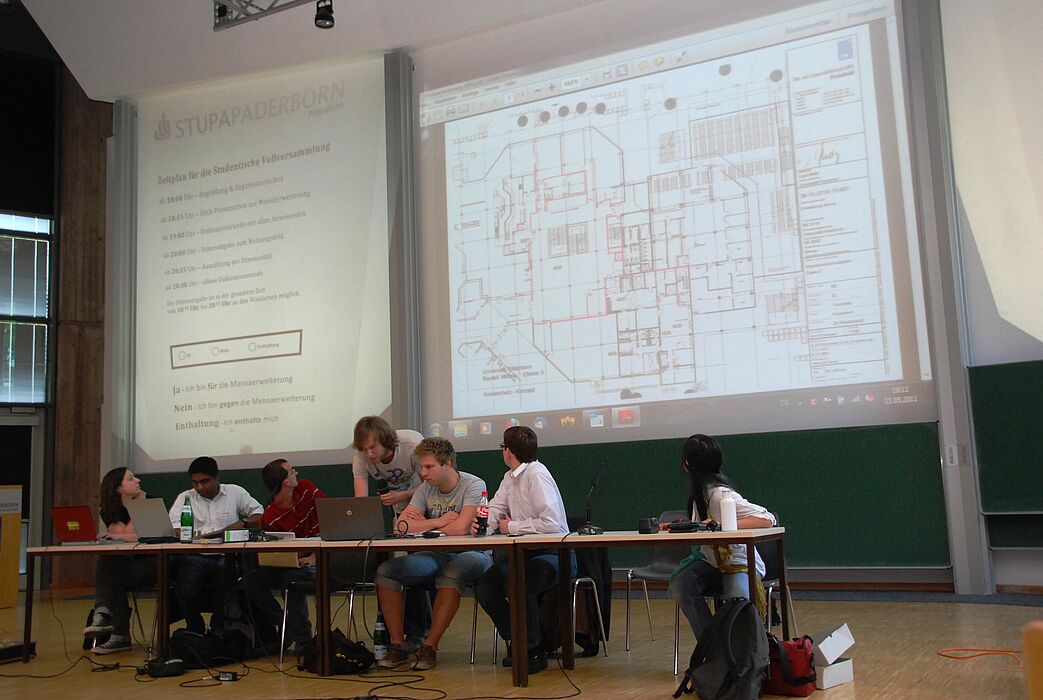 Foto (Universität Paderborn, Christopher Streicher): AStA-Vorsitzender Christoph Husemann (stehend) zeigte die Baupläne für den Mensa-Ausbau.