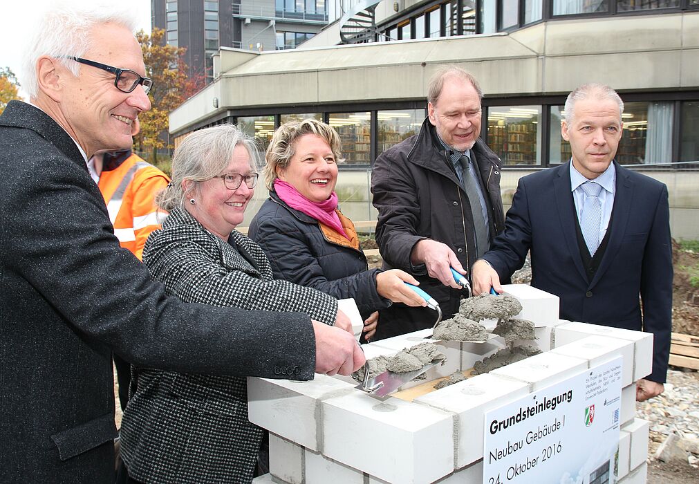 Foto (Universität Paderborn, Vanessa Dreibrodt): Griffen zur Maurerkelle: (v. l.) Martin Pantke, stellv. Bürgermeister Stadt Paderborn, Simone Probst, Vizepräsidentin der Universität Paderborn, Svenja Schulze, NRW-Wissenschaftsministerin, Rolf Holler,