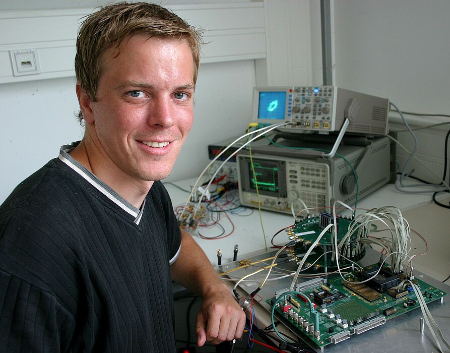 Foto (Stefan Freundlieb): Dipl.-Ing. Timo Pfau vom Institut für Elektrotechnik und Informationstechnik der Universität Paderborn vor einigen elektrischen Geräten des komplizierten Empfängers.