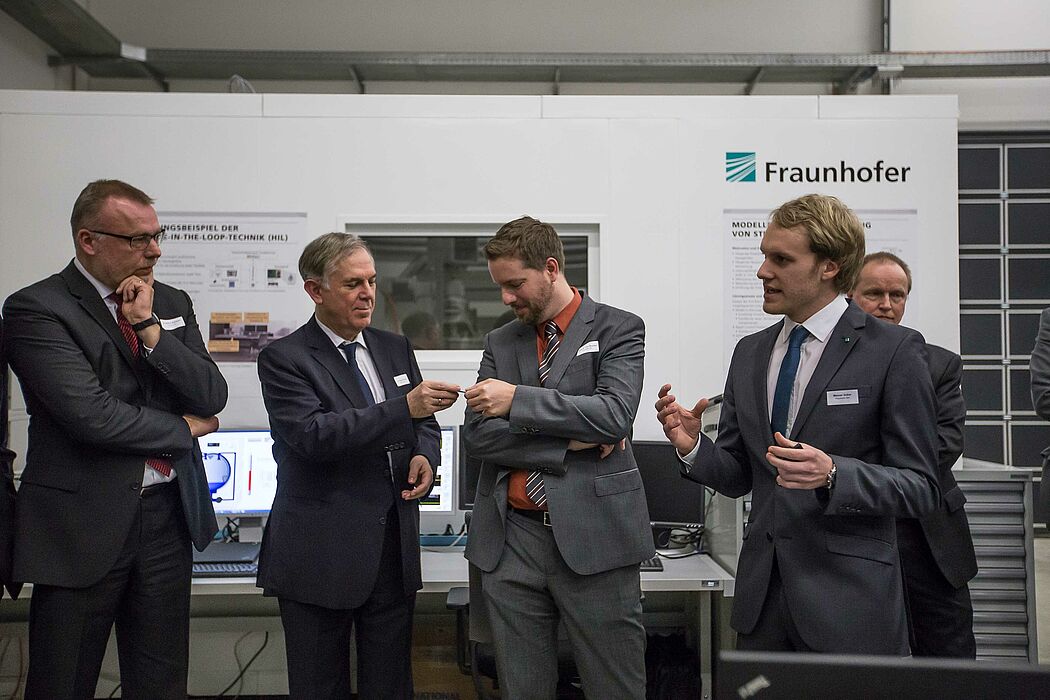Foto: Eine Station des Institutsrundgangs war der Versuchsstand für einen selbstkorrigierenen Stanzbiegeprozess. V. l. n. r.: Dr. Stefan Schwehr (paragon AG), Dr. Eduard Sailer (Miele & Cie. KG), Prof. Dr. Eric Bodden (Universität Paderborn/Fraunhofer I
