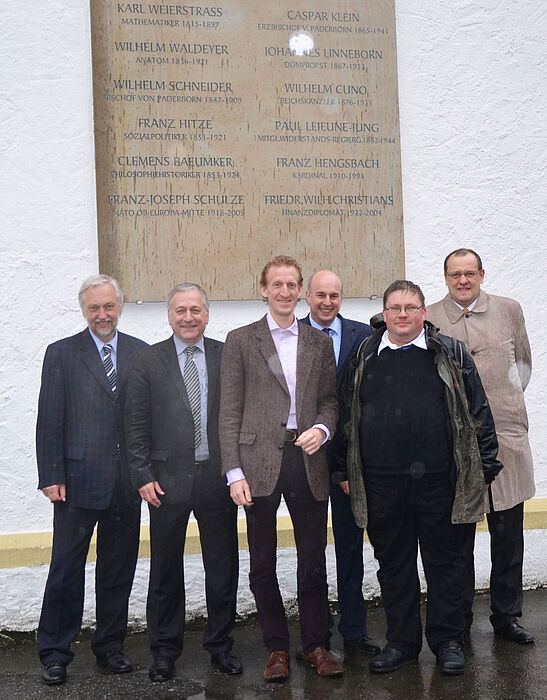 Abbildung: Trotz Regen gutgelaunt vor der Gedenktafel am Gebäude des Gymnasiums Theodorianum, v. l. n. r.:Prof. Dr. Wilhelm Schäfer (Vizepräsident für Forschung und wissenschaftlichen Nachwuchs der Universität Paderborn), Dr. Michael Laska (Geschäft