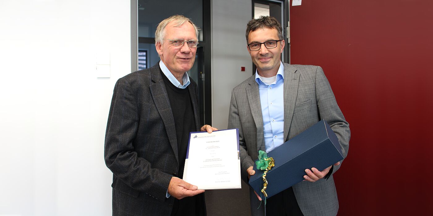 Foto (Universität Paderborn, Frauke Döll): Zusammen mit dem Jubilar Prof. Dr. Joachim Fischer (links) freut sich Prof. Dr. Martin Schneider, Dekan der Fakultät für Wirtschaftswissenschaften, im Kreise der Kolleginnen und Kollegen auf der Fakultätsrat