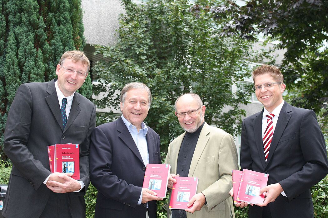 Foto (Universität Paderborn, Martin Decking): Herausgeber Dr. Ingo-G. Wenke (3. v. li) überreicht Dr. Michael Laska (2. v. li.), Geschäftsführer Fakultät für Elektrotechnik, Informatik und Mathematik, 50 Exemplare des neuen Buches „Arbeitsmarkt El