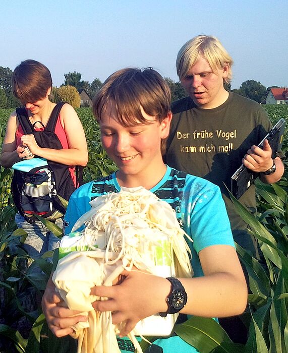 Foto (Universität Paderborn): Sicher geborgen: Finnegan Pichnik findet die Styroporbox mit der Kamera und dem GPS-Tracker in einem Maisfeld nahe Delbrück.