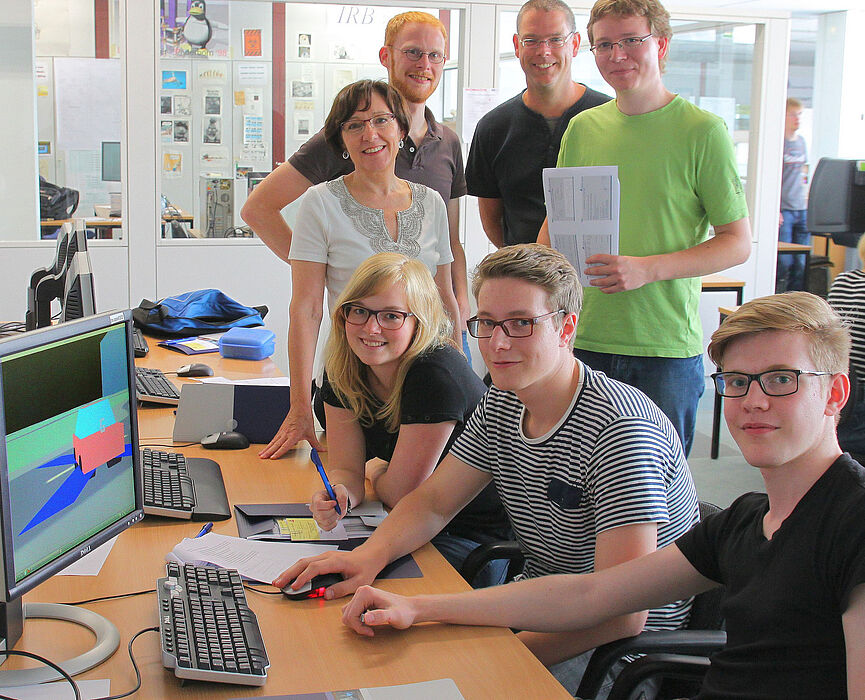 Foto (Thomas Thissen): Schüler aus dem Gymnasium Delbrück (am Tisch, v. l.) Teresa Göstenmeier, Marvin Düsterhus und Cedric Richter gemeinsam mit (hintere Reihe, v. l.) Prof. Dr. Gitta Domik-Kienegger, Dipl.-Inf. Stephan Arens, Dr. Hauke Friedrich und