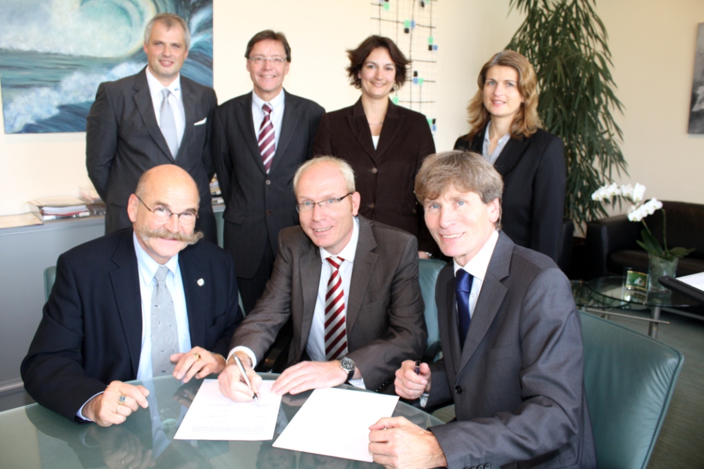 Foto (Frauke Döll): Kanzler Jürgen Plato (links), Präsident Prof. Dr. Nikolaus Risch (rechts)  und Karl-Julius Sänger, Vertriebsleiter OWL der Techniker Krankenkasse, unterzeichnen im Beisein von Hans-Norbert Blome (hinten links), Hochschulberater der