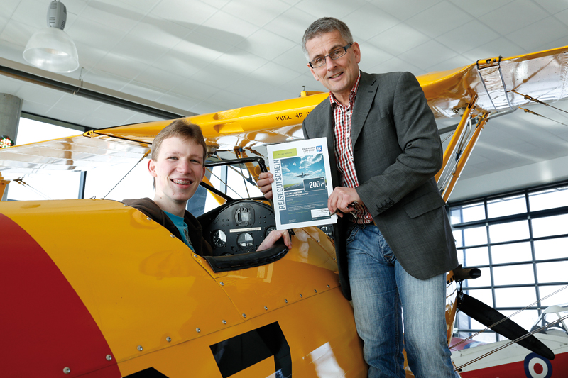 Bild: Jonas Homburg nimmt seinen Preis vom Chef des Flughafens Paderborn-Lippstadt Elmar Kleinert in einer Boeing Stearman PT-17 aus dem Jahr 1941 entgegen.