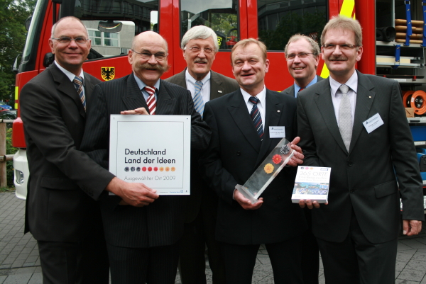 Foto (C.I.K.): Der Preisträger und die Festredner vor einem Feuerwehreinsatzwagen (v.l.n.r.): Prof Dr.-Ing. Detmar Zimmer (Dekan der Fakultät für Maschinenbau der Uni Paderborn), Jürgen Plato (Kanzler der Uni Paderborn), Heinz Paus (Bürgermeister der