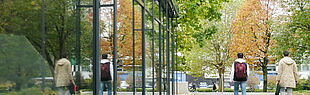 Zwei Personen spiegeln sich in der Glasfront der Mensa der Universität Paderborn.